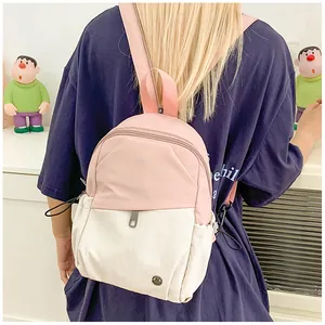Pink and white backpack detail showing side drawstring pocket and metal logo on a model