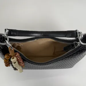 Minimalist black woven leather underarm bag with zipper closure and charm pendant