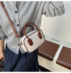 Detail of canvas and brown leather bowling bag with twin handles and crossbody strap