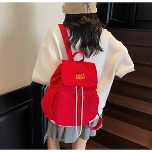 Dettaglio dello zaino in nylon rosso con chiusura a coulisse e ricamo giallo acceso