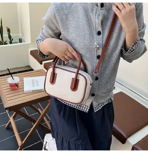 Close-up of a retro canvas Boston bag with brown leather trim in a cozy cafe setting