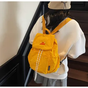 Dettaglio dello zaino in nylon giallo impermeabile con coulisse bianca e ricamo rosso