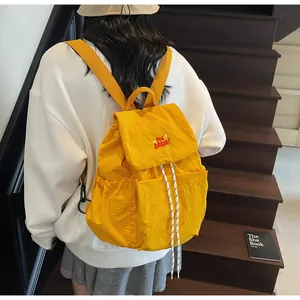 Dettaglio dello zaino in nylon giallo con ricamo rosso e chiusura con coulisse regolabile