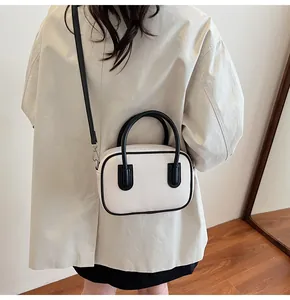 Detail view of a vintage off-white Boston bag with black leather trim and crossbody strap