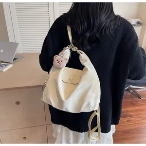 Detail view of cream soft faux leather tote bag with brown plush bear charm and wide straps