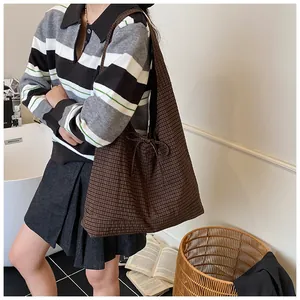 Detail of canvas tote bag with brown plaid pattern and decorative side ribbon bow