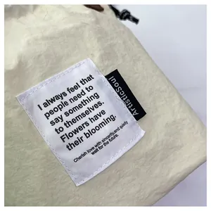 Detalle de la bolsa de almuerzo beige con tela texturizada y etiqueta tejida blanca