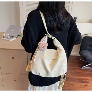 Detail view of cream white large capacity tote bag with bear charm on model shoulder