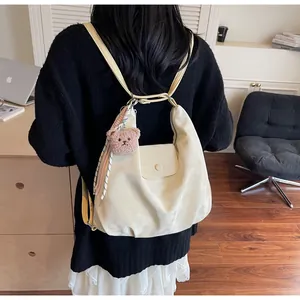 Detail view of cream white tote bag with cute bear charm and striped scarf decoration