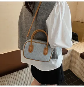 Detailed view of grey textured bowling bag with brown leather handles on a model