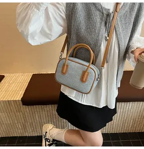Detail of light blue woven mini Boston bag with brown leather handles and shoulder strap