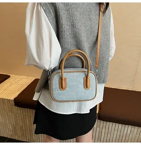 Detail of light blue textured Boston bag with brown leather handles and silver hardware