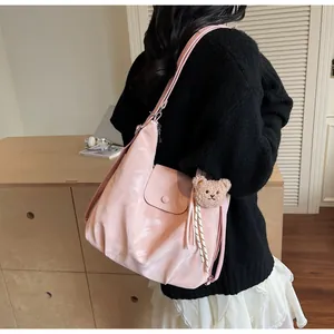 Detail showing soft pink leather tote bag with a cute bear pendant on a model