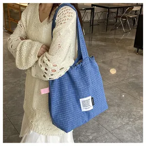 Detail of navy blue checkered canvas tote bag with artistic label and side tags