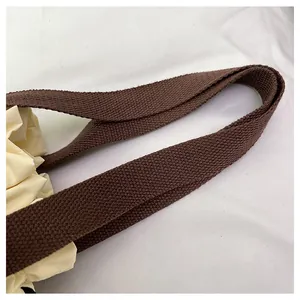 Detalle de la correa tejida marrón y textura de tela beige en bolsa térmica