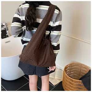 Detail of dark brown checkered tote bag with a decorative ribbon bow on a textured fabric