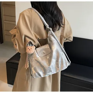 Silver metallic tote with a pink plush bear charm worn by a model in a minimalist setting