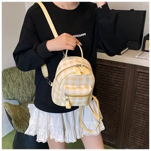 Detail view of a yellow checkered mini backpack on model showing strap fit and sizing