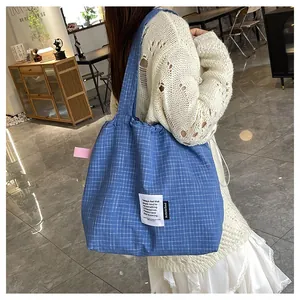 Detailed close-up of blue checkered canvas tote bag with drawstring and fabric label