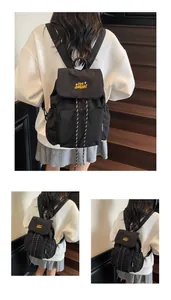 Dettaglio di uno zaino in nylon nero con chiusura a coulisse e ricamo giallo