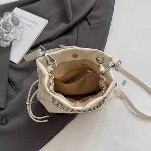 Chic beige leather bucket bag featuring a brown fabric lining and silver chain strap
