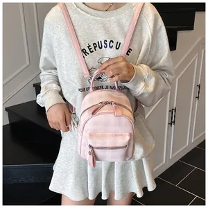 Detail view of the pink and white plaid mini backpack with dual zippers and leather texture