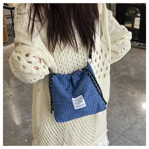 Detail view of blue checkered canvas tote bag with drawstring closure and woven strap