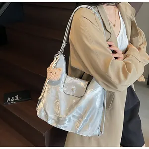 Silver faux leather tote bag with front flap pocket and cute bear charm on model