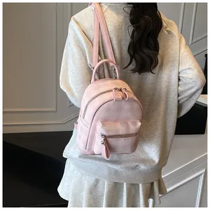 Detail of pink plaid mini backpack featuring front zipper pocket and silver metal hardware