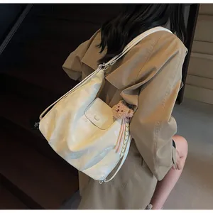 Detail of a creamy white large hobo bag with teddy charm and scarf on a model