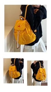 Dettaglio dello zaino in nylon giallo brillante con chiusura a coulisse e tasche laterali