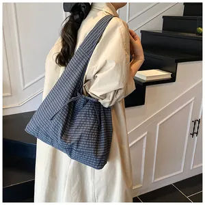 Side view of a large blue checkered tote bag with a bow tie detail on a model