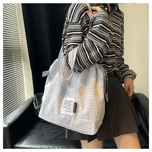 Close-up of checkered drawstring tote bag showing detailed texture and artistic fabric label