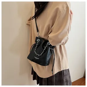 Detail of black leather bucket bag with silver chain strap and drawstring closure