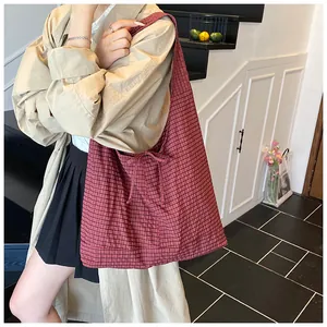 Detailed view of red checkered tote bag with side bow tie detail on model