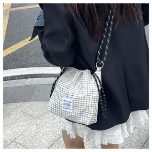 Detail of blue plaid canvas drawstring tote with braided strap and stylish brand label