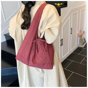 Macro detail of red plaid tote bag with side ribbon bow on textured fabric