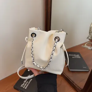 Creamy white leather bucket bag with silver chain handle and minimalist crossbody strap