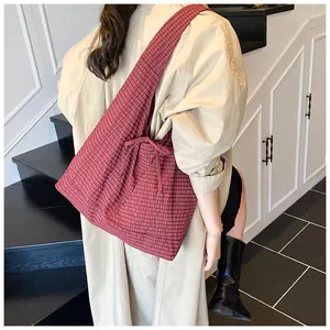 Detailed view of red plaid tote bag with bow tie knot detail on model with trench coat