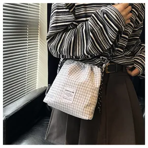 Detail of blue and white checkered drawstring tote bag with woven rope shoulder strap