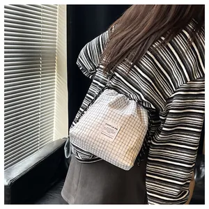 Detail view of a blue and white checkered drawstring tote bag with an adjustable cord