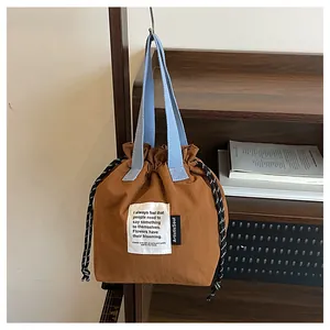 Detalle de bolsa de lona para almuerzo con cordón y asa azul colgada en madera