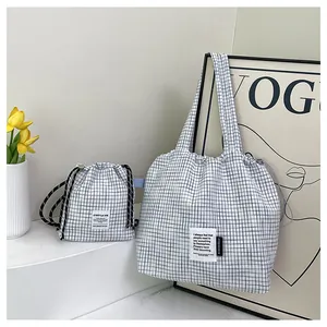 Detail of checkered tote bag with drawstring pouch featuring C'EST LA VIE fabric label