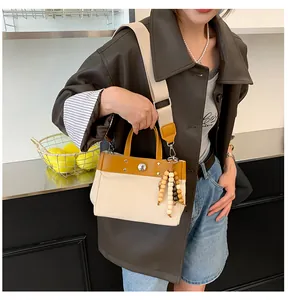 Detalle del bolso tote de lona con ribete de cuero y colgante de borlas de cuentas