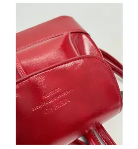 Detail of red glossy leather texture with MEIHAO embossed lettering on a vintage backpack