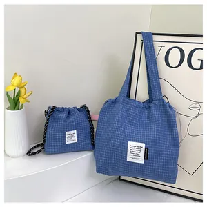 Detail of blue checkered tote bag and drawstring pouch on a minimalist white platform