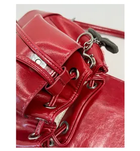 Detail of red glossy leather backpack featuring silver eyelets and green bow charm