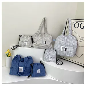 Detail of blue and gray checkered tote bags and drawstring pouches on white steps