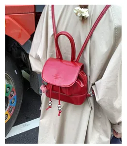 Close-up of vintage red leather backpack featuring drawstring and checkered charm detail
