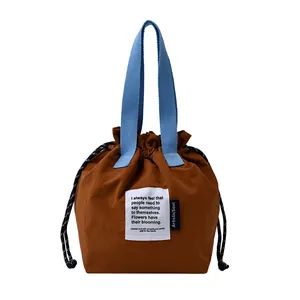 Bolsa térmica marrón con asas azules de cordón y etiqueta artística de tela